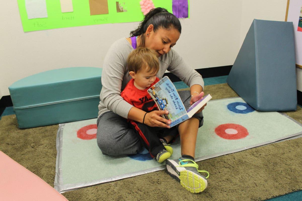 一名SJC儿童与家庭发展中心的讲师在幼儿教室里给一名幼儿朗读